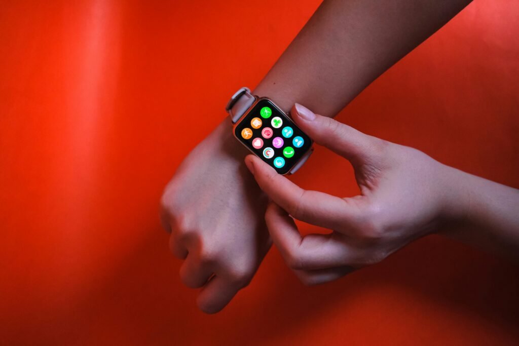 A close-up image of hands interacting with a smart watch against a vibrant red background, highlighting modern technology and connectivity.